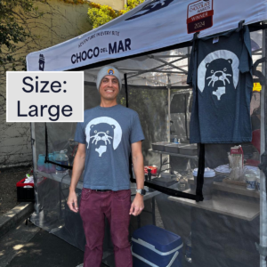 A person standing with a shirt that has Cleo Otter the mascot of Choco Del Mar on it. Size: Large