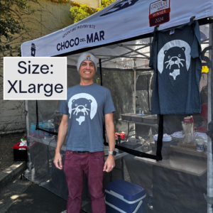A person standing with a shirt that has Cleo Otter the mascot of Choco Del Mar on it. Size: Extra Large